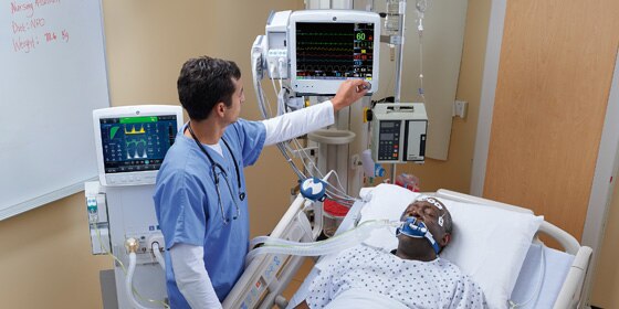 A caregiver uses GE Healthcare CARESCAPE B650 monitor to do patient monitoring in a hospital room.