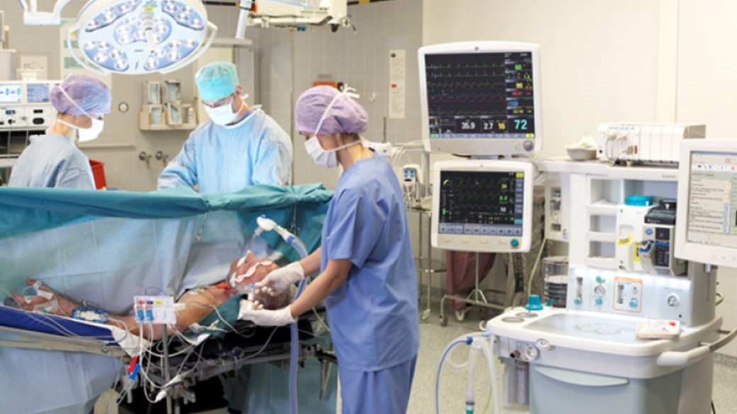 Three clinicians performing surgery on a patient 