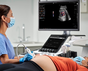 Female clinician performing an OBGYN ultrasound scan on a reclined patient