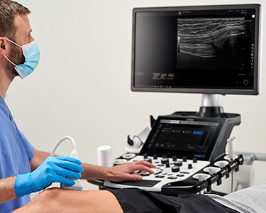 Male clinician performing an ultrasound exam of the knee
