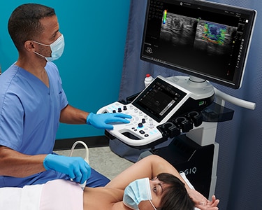 Male clinician peforming a breast ultrasound exam on a female patient