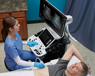Female clinician scanning a male patient's abdomen to perform a liver scan