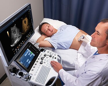 Male clinician performing an abdominal ultrasound exam on a male patient