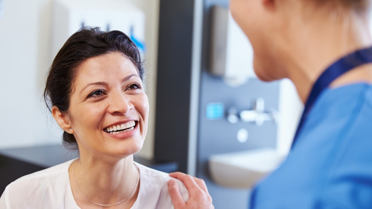middle aged woman smiling and talking to a healthcare worker