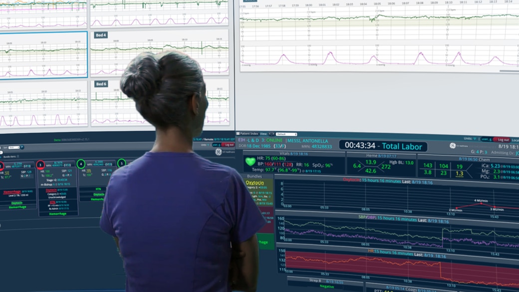 nurse looking at four giant monitors with analytis and patient vital signs